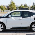 충전 커넥터가 연결된 전기차 측면과 충전소 배경