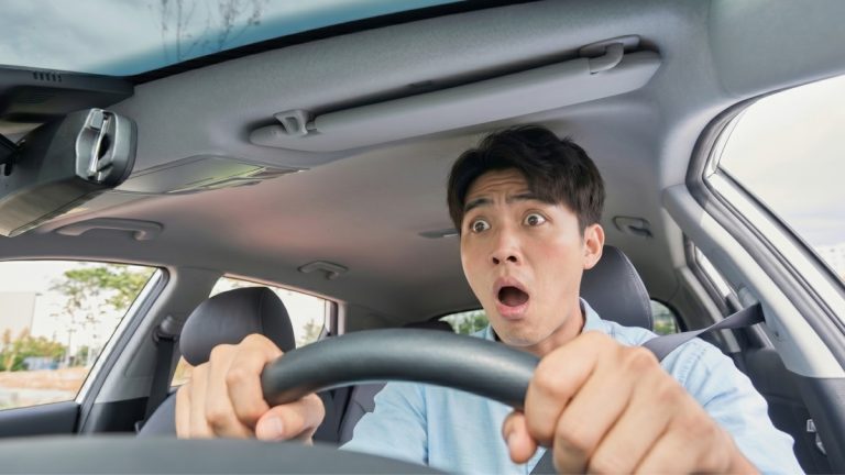 운전석에서 당황한 표정으로 운전대를 꽉 잡고 있는 운전자