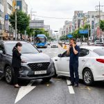 교통사고 현장에서 운전자가 보험사와 통화하는 장면